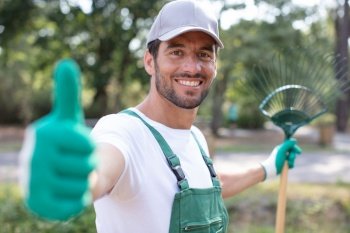 happy professional gardener with green gloves giving a thumbs up