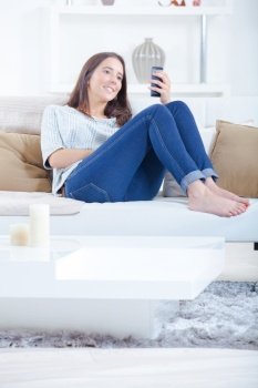 Girl sat on couch using smartphone