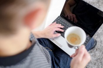 man with a cup of tea working on his laptop