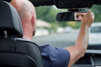 man adjusting rear-view mirror inside the car