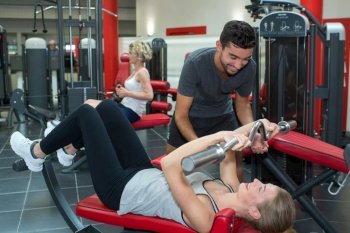 personal fitness trainer assisting young woman in the gym