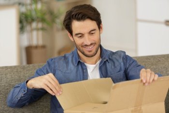 happy man opening parcel box at home