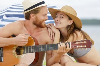 beautiful young people with guitar on beach