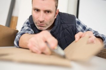 man cuts a roll of paper with a stationery knife