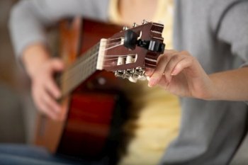 cropped view of woman tuning a guitar