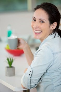 cheerful woman enjoying a coffee at home