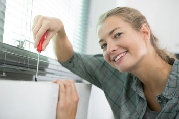 happy woman installing blinds with screwdriver