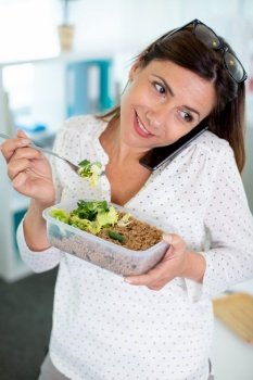beautiful young woman using smartphone device while eating a salad