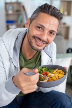 young man eating vegetarian salad with appetite