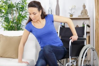 disabled woman in wheelchair moving to the sofa