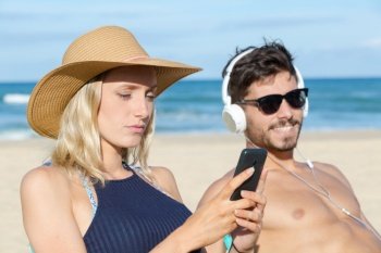 couple using their phones on the beach