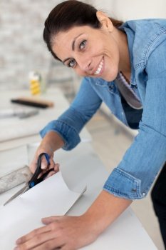 a cheerul woman cutting wallpaper