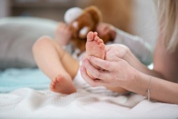 mother does a foot massage to a newborn baby