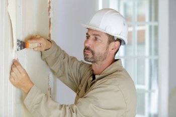 professional male builder stripping wallpaper