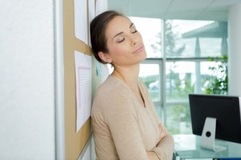 businesswoman leaning against wall in office