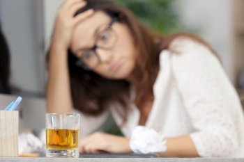 woman very stress and drinks whiskey on workspace