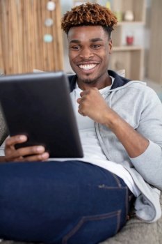 happy man browsing in a tablet sitting on a couch