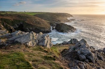 Beautiful sunset landscape image of Cornwall cliff coastline with tin mines in background viewed from Pendeen Lighthouse headland