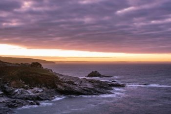 Moody landscape sunrise image at Prussia Cove in Cornwall England with atmospheric sky and ocean