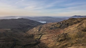 Aerial drone landscape image of sunrise Winter view from Red Screes in Lake District looking towards Windermere in the distance over Wansfell Pike peak