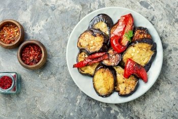 Roasted eggplant and grilled bell pepper on stone or concrete background, top view. Grilled eggplant slices