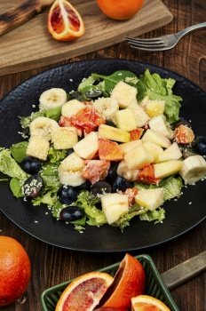 Raw fruit salad of red orange, apple, banana and herbs.. Summery fruit salad with oranges.