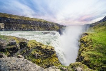 The Icelandic waterfall Gullfoss surrounded by green moss on the cliffs in the sunset