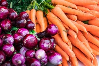 resh orange carrots and purple red onion on farmers market