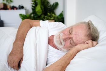 senior man sleeping alone and headache or dreaming nightmare on bed in room