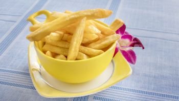 Cups of French fries on table with fresh purple orchid. Cups of French fries 
