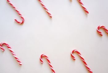 Flat lay of candy cane with copy space for text on yellow background, holiday concept