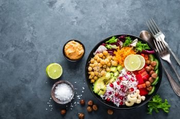 Healthy vegetarian Buddha bowl with fresh vegetable salad, rice, chickpea, avocado, sweet pepper, cucumber, carrot, pomegranate and nuts closeup. Healthy vegetarian Buddha bowl with fresh vegetable salad, rice, chickpea, avocado, sweet pepper, cucumber, carrot, pomegranate and nuts