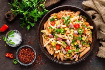 Spicy pasta penne bolognese with vegetables, beans, chili and cheese in tomato sauce