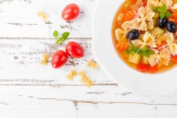 Minestrone, vegetarian soup with pasta and vegetables on white wooden rustic background. Traditional italian food. Top view