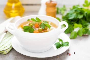 Summer light vegetarian vegetable soup with carrot, potato, cabbage and grean peas on white background. Diet healthy and tasty lunch. Baby food