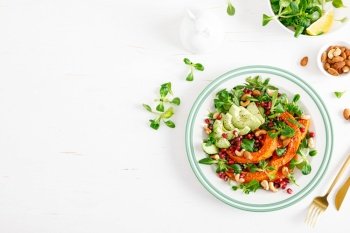 Fresh vegetable salad with lambs lettuce, baked butternut squash or pumpkin, avocado, pomegranate, cashew and almond nuts. Healthy vegetarian food concept. Top view