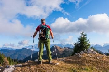 Hiker with backpack is stand on mountain top.