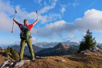Hiker cheering elated and blissful with arms raised in the sky after hiking.