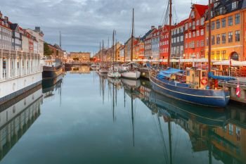 Multicolored facades of old medieval houses and ships along the canal of Nyhavn. Denmark. Copenhagen.. Copenhagen. The Nyhavn channel is at dawn.