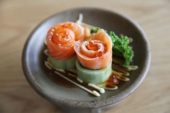 Salmon sashimi with cucumber on wood