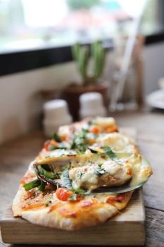 pizza with seafood and tomatoes on a wooden table , italian food