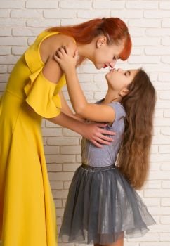 Little girl gently hugs and stretches to kiss her mom. mother with daughter