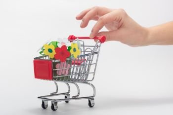 Hand carries a grocery cart with a children’s crafts bouquet of flowers