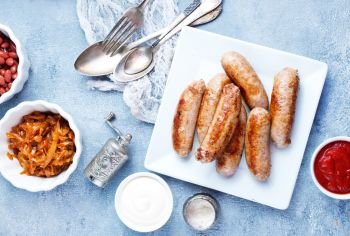 sausages on white plate, fried sausages with sauce