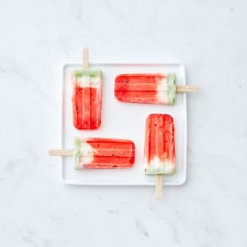 Ice lolly. Homemade ice cream in the form of a square in a white plate on a gray marble background with space for text. Sweet summer dessert. Flat lay. Pattern of ice cream on a stick in the shape of a square on a white plate on a gray marble background with copy space. Flat lat