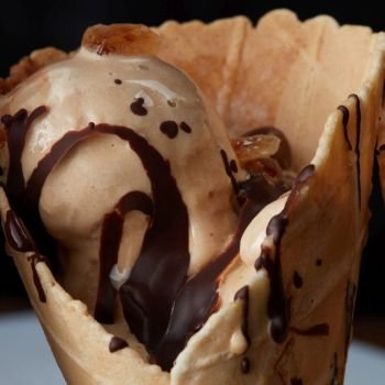 Close-up ice cream with chocolate syrup in a waffle cone. Delicious ice cream In waffle cone