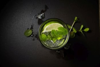 Cold and refreshing infused detox water with lime and mint leaves isolated on black, flat lay. Cold and refreshing infused detox water with lime and mint in a glass