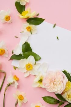 Top view of flowers covering blank copy space where ideas, emotions may be noted. White flowers with green leaves represented over pink background.. Flowers covering blank copy space