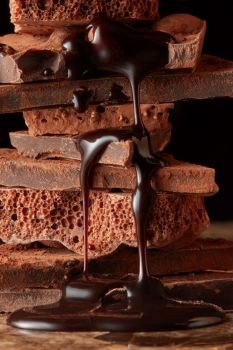 chocolate syrup dripping on stack dark chocolate. Heap of broken pieces chocolate