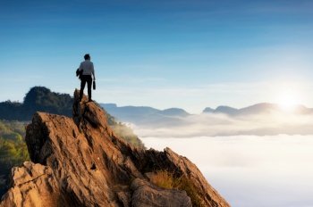 Concept vision, Young businessman wearing comfortable casual suit jacket standing holding business bag on top of peak mountain and looking forwards, success, competition and leader concept.. businessman looking forwards.